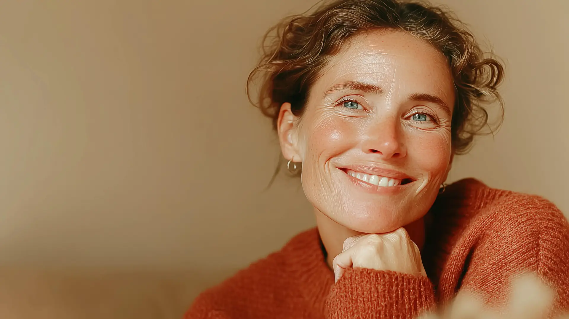 Femme souriante en pull orange regardant la caméra